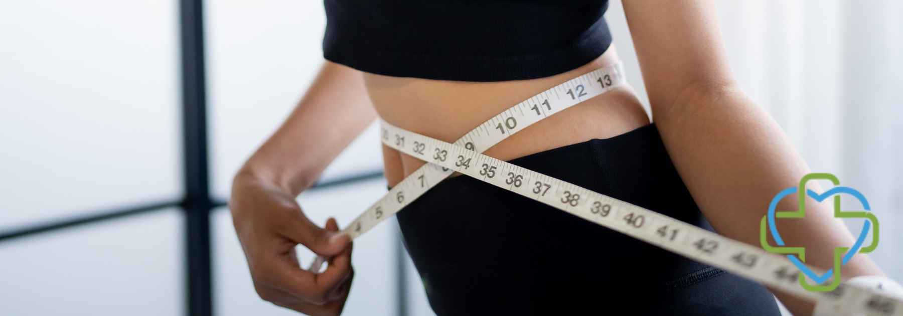woman in dark workout gear measuring waist