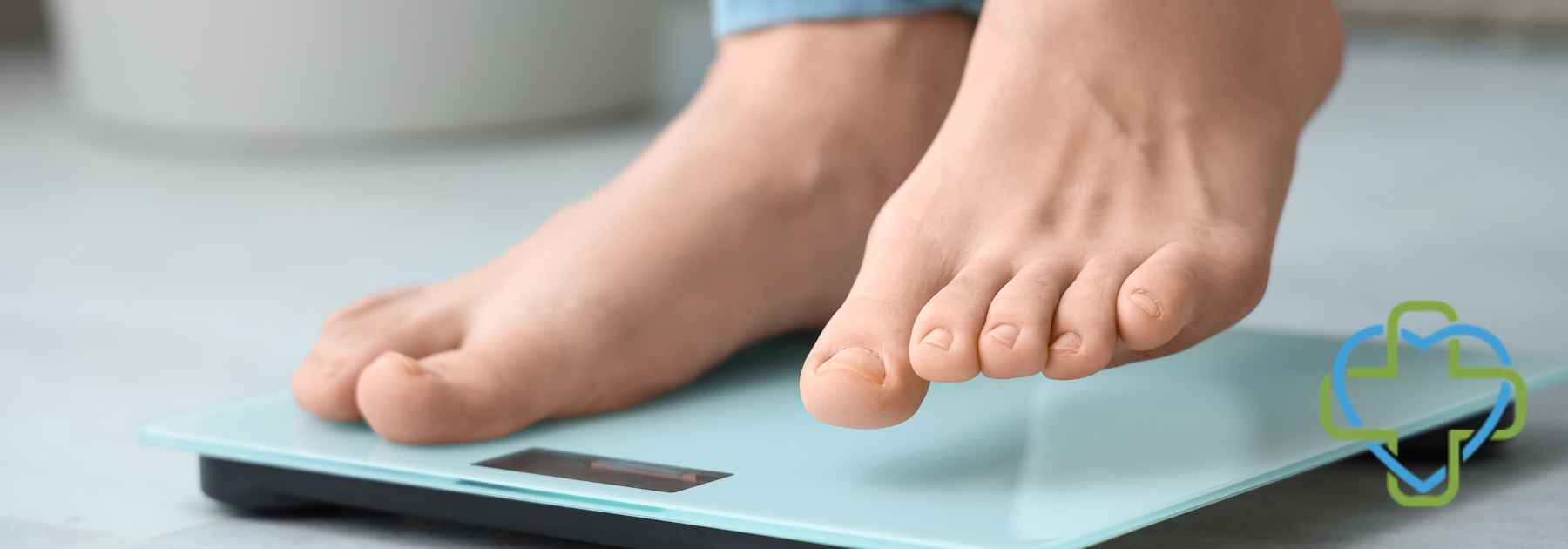 person in bare feet and jeans stepping on scales