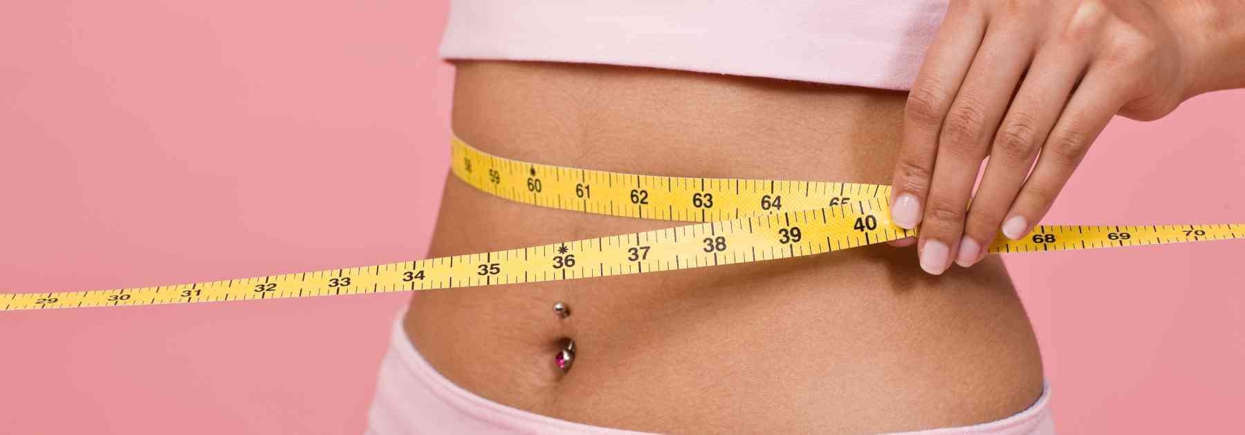 woman in pink clothes measuring waist