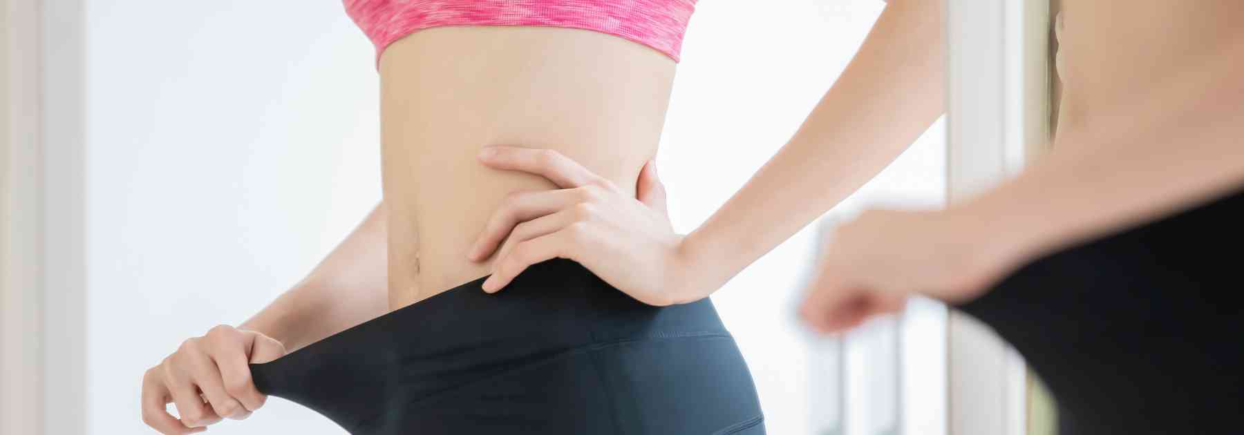 woman looking in mirror wearing leggings too big