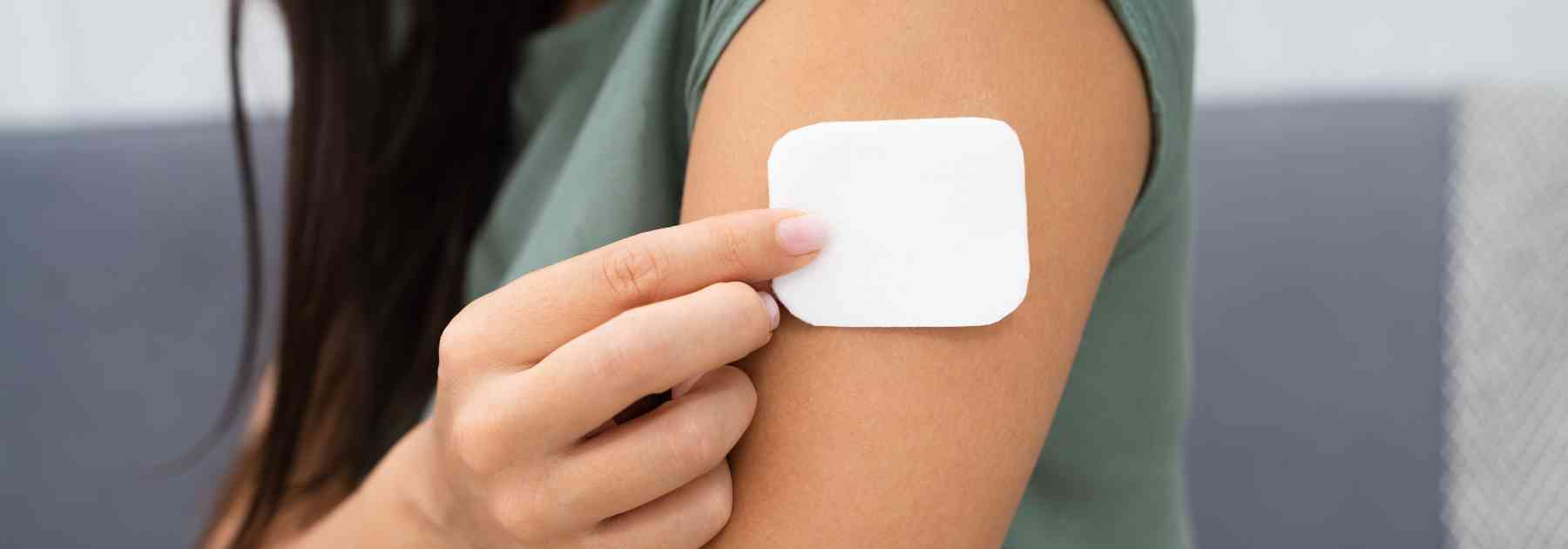 young woman placing white patch on her arm
