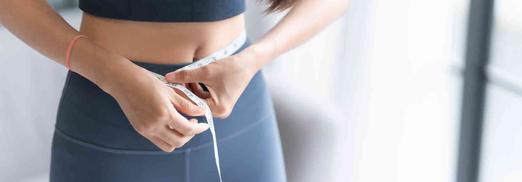 woman in workout gear measuring her waist