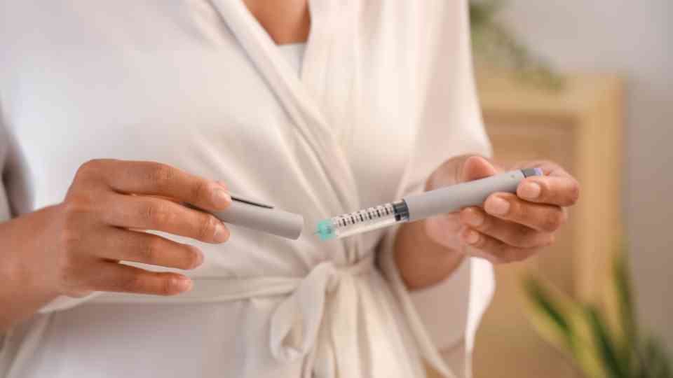 woman in white dressing gown holding weight loss injection