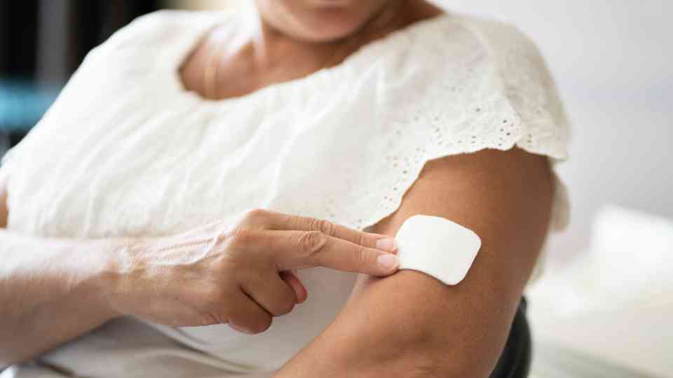 woman placing white patch on her arm