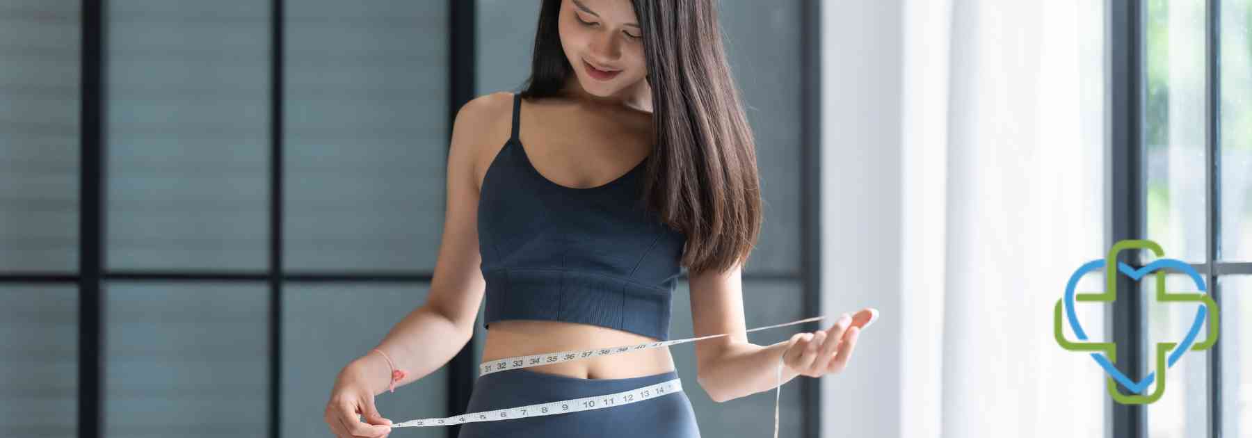 young woman in workout gear measuring waist