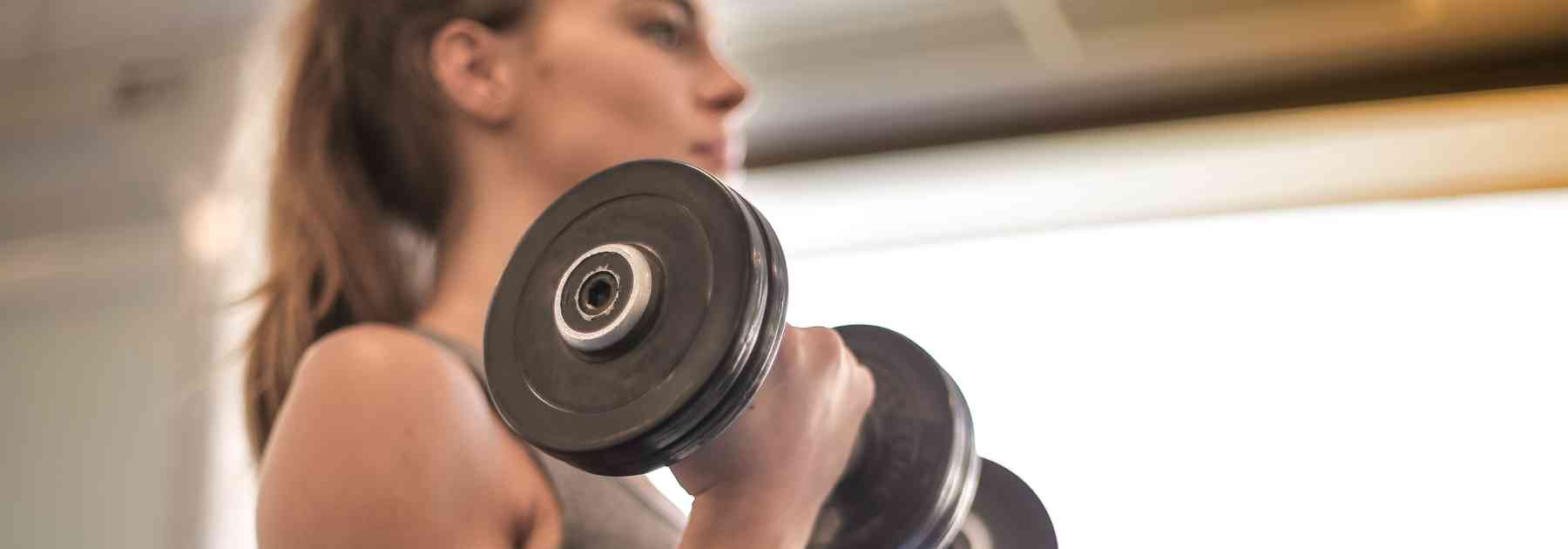young woman lifting weights in gym