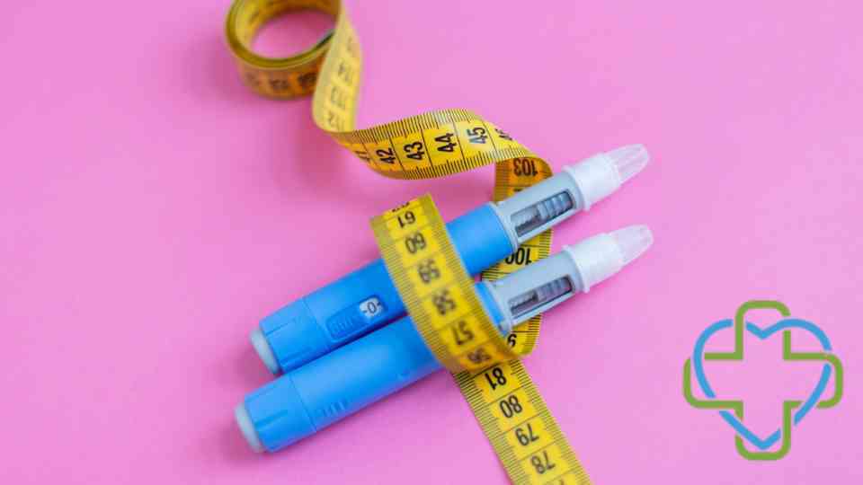 two weight loss injections wrapped in measuring tape on pink background
