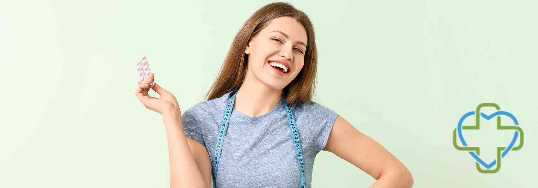young woman smiling holding weight loss pills on green background