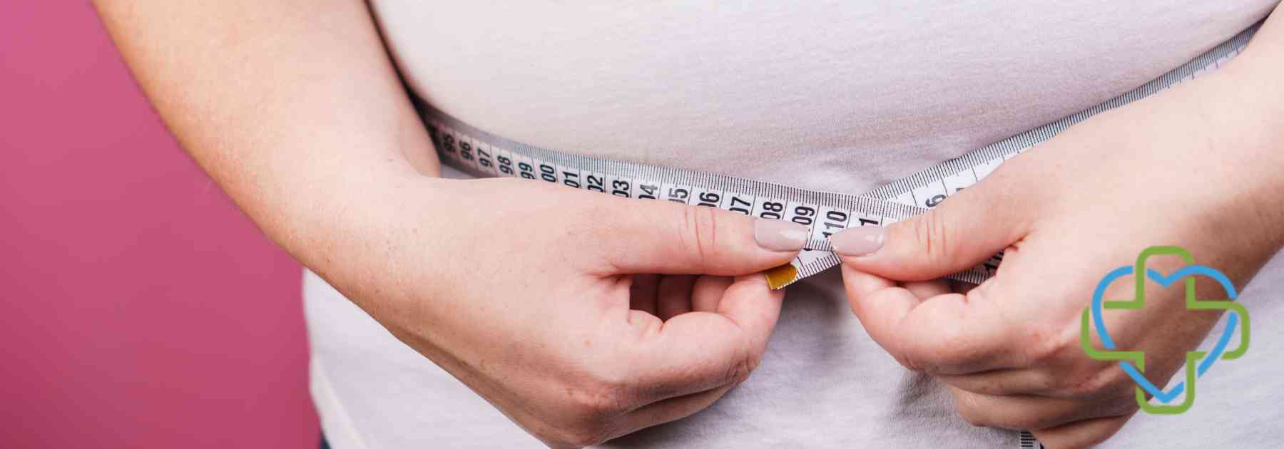 overweight woman measuring waist on pink background