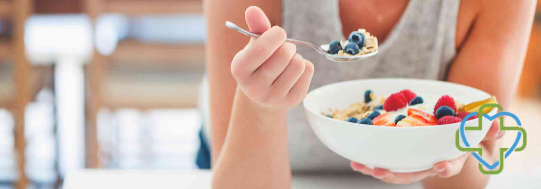 woman eating berries from bowl with spoon