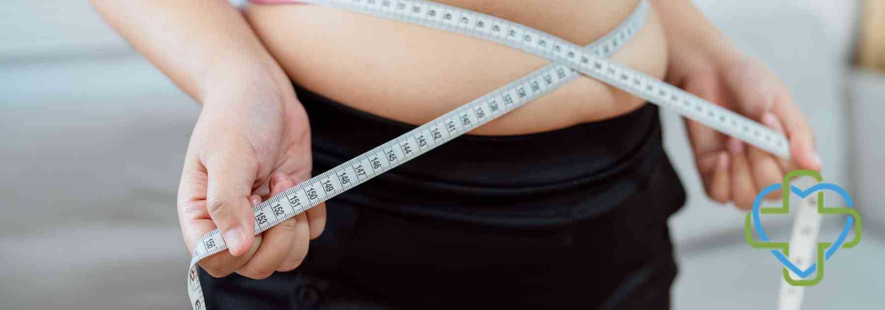 overweight woman in crop top measuring waist