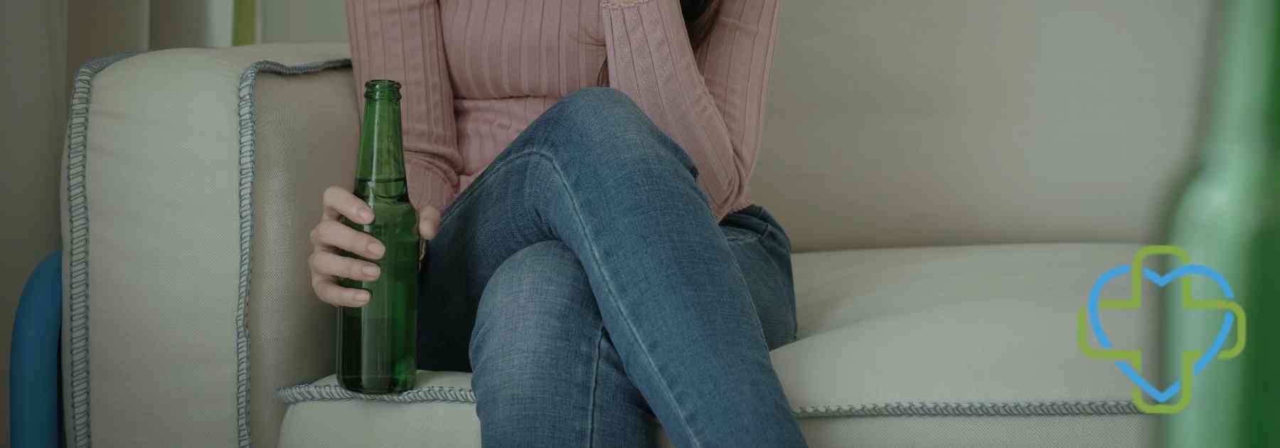 woman sitting on couch holding beer bottle