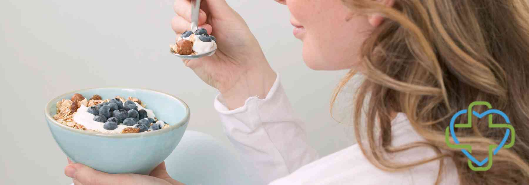 woman eating berries from bowl with spoon