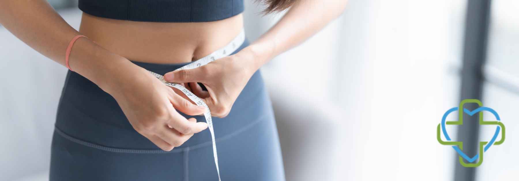 woman in grey workout gear measuring waist