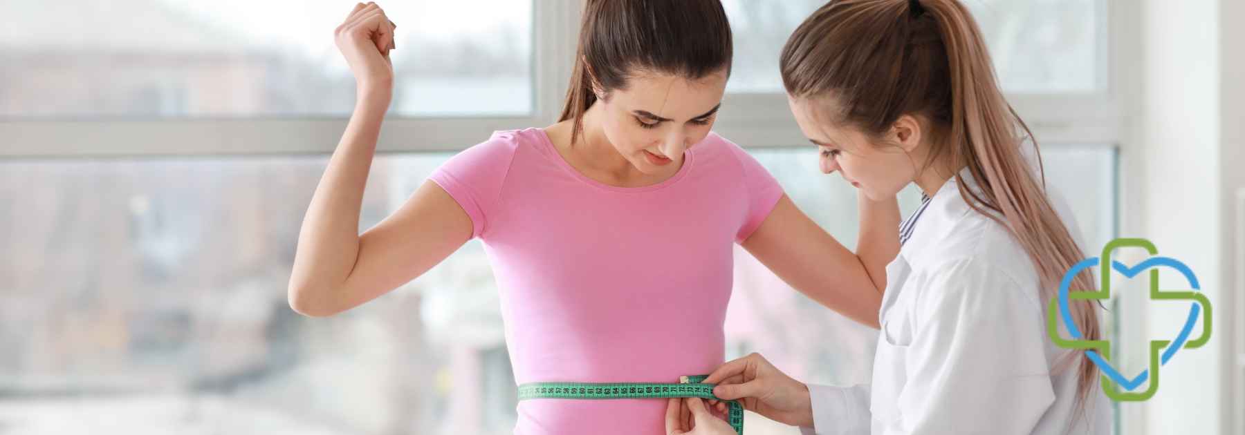 female doctor measuring waist of young female patient