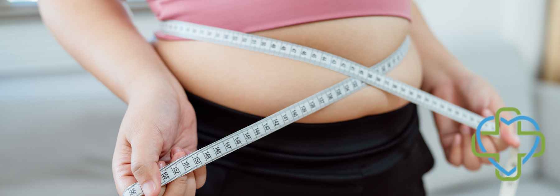 overweight woman wearing pink crop top measuring waist